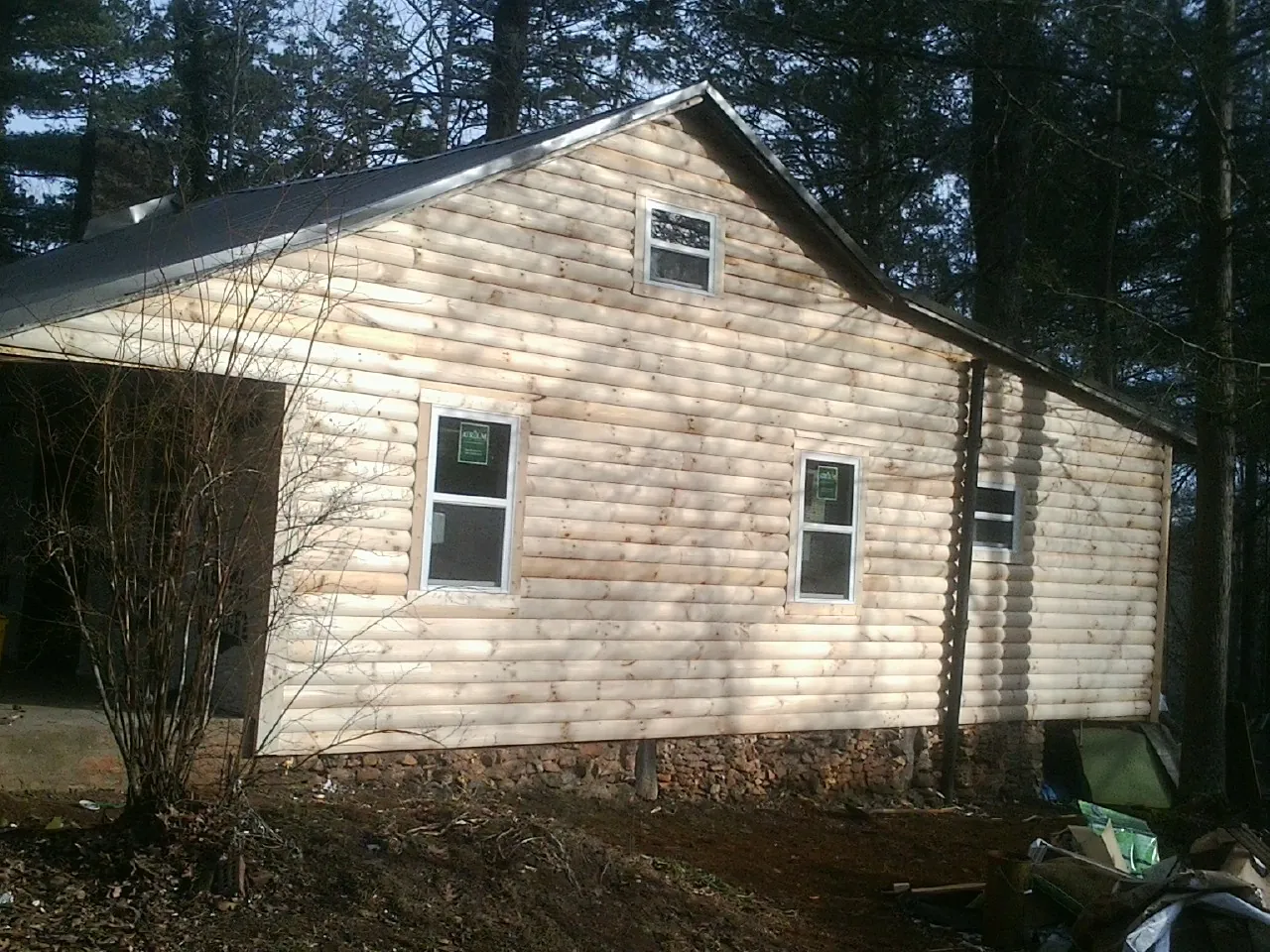 New log siding and dark metal roofing on a gable end in Goose Creek