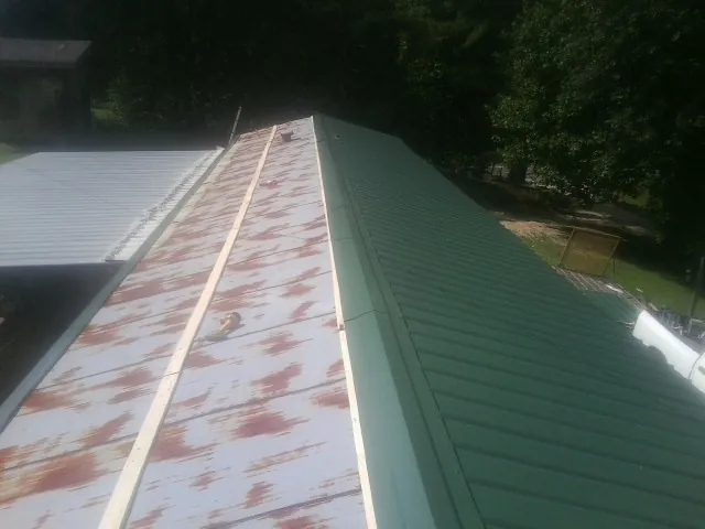 Old rusted panels beside newly installed green metal roofing — Wind Damage Roof Repair by Roofing Brothers in Goose Creek