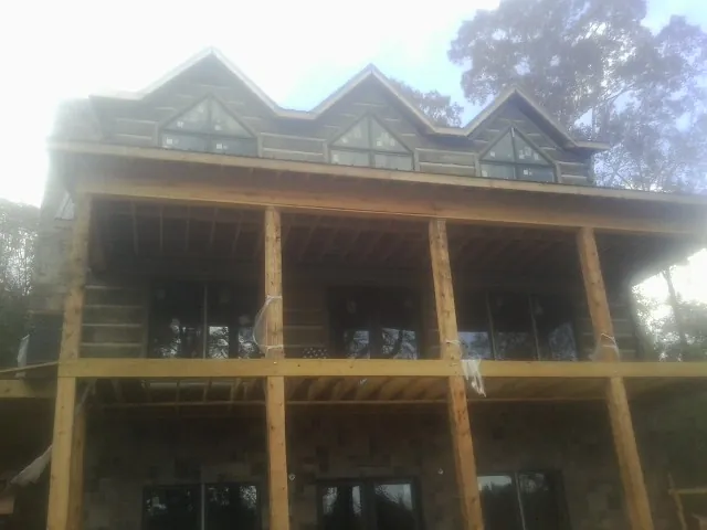 Dormers and porch framing on a large log home under construction — Roof Coating work by our crew in Goose Creek