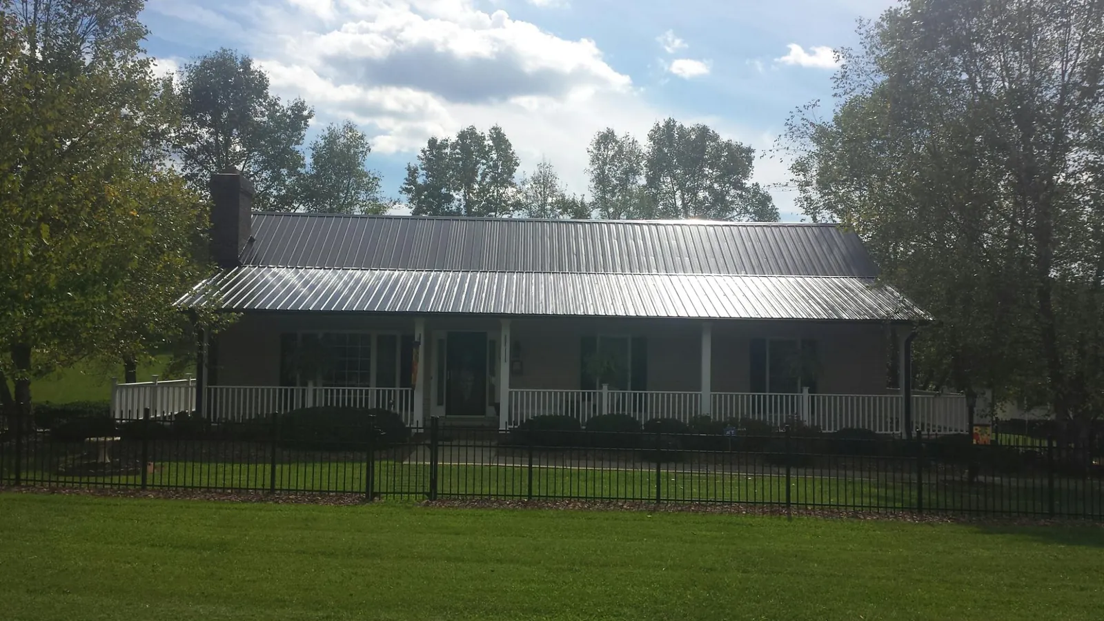 Gray metal roof on a brick ranch with a full width front porch — Gutter Guard Installation work by our crew in Goose Creek