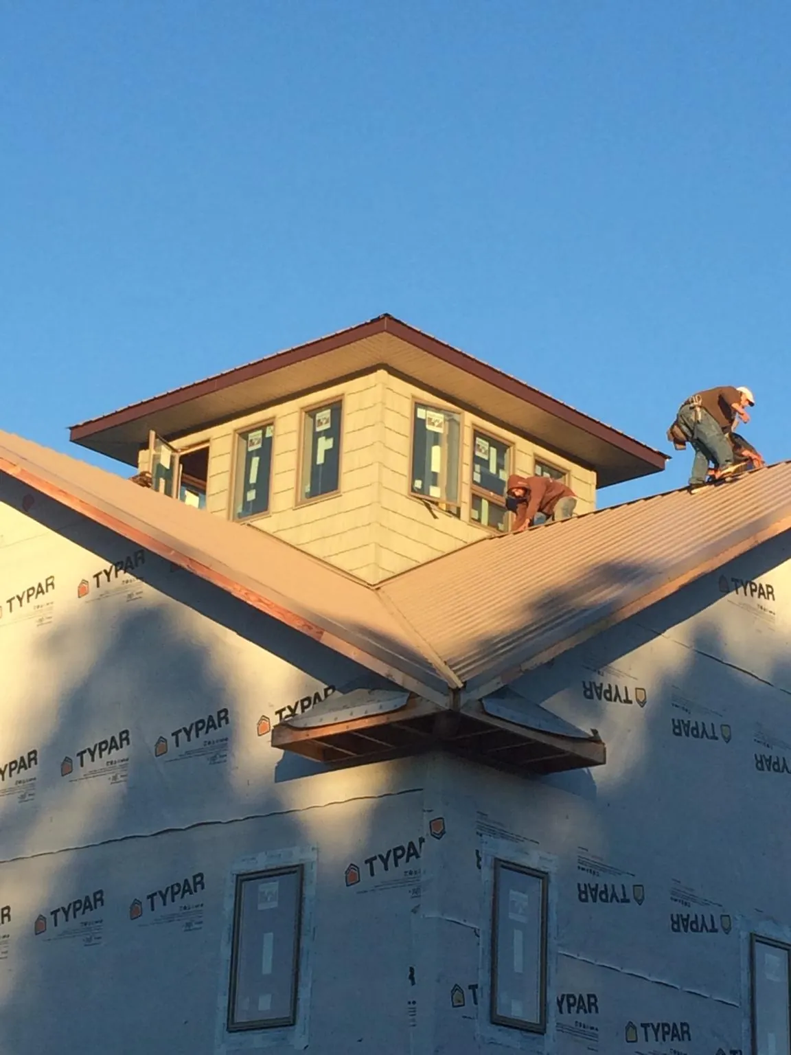 Roofers working around a rooftop cupola on a new metal roof at sunset — Roof Waterproofing in Goose Creek by Roofing Brothers